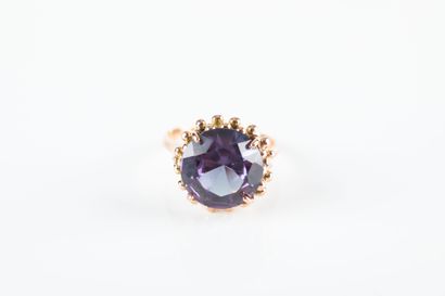 Gold ring holding a synthetic purple sapphire...