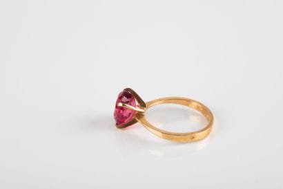 Yellow gold ring holding an oval-cut pink...