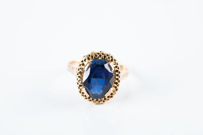 Yellow gold ring holding an oval synthetic...