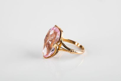 Yellow gold ring holding a shuttle-cut pink...