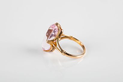 Yellow gold ring holding a shuttle-cut pink...