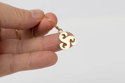 Yellow gold forcat chain holding a triskel...
