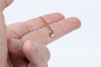 Yellow gold forcat chain holding a drop pendant...