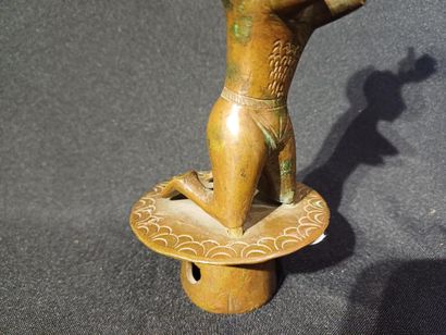 Kneeling figure on a pedestal, raising his...