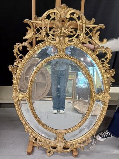 Oval wood and gilded stucco mirror with shell...