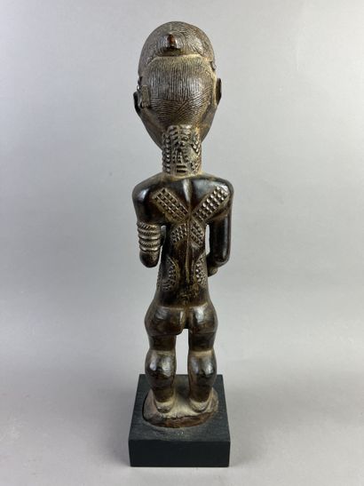 Male ancestor shown standing, holding a long...