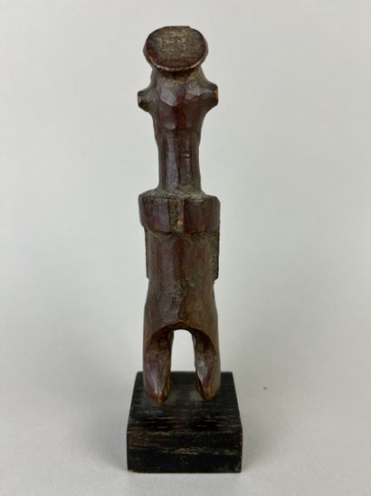 Small fetish with flat headdress, shown standing...