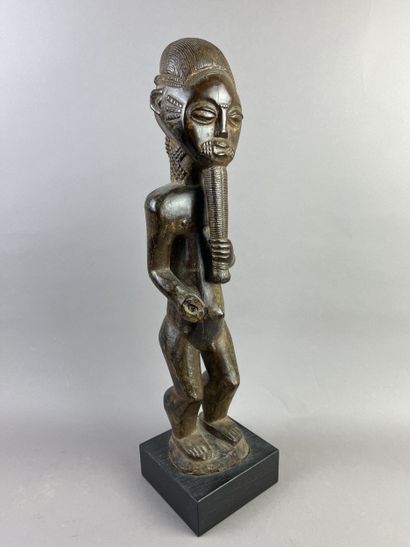 Male ancestor shown standing, holding a long...