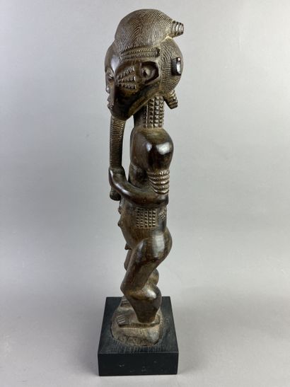 Male ancestor shown standing, holding a long...