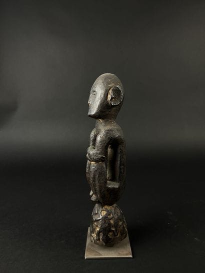Small seated figure, arms crossed over knees,...