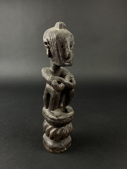 Seated figure with arms resting on knees....