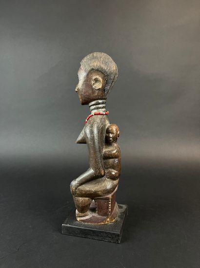 Mother seated on a stool with her child on...
