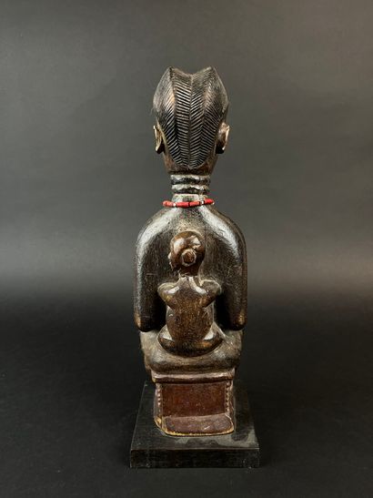 Mother seated on a stool with her child on...