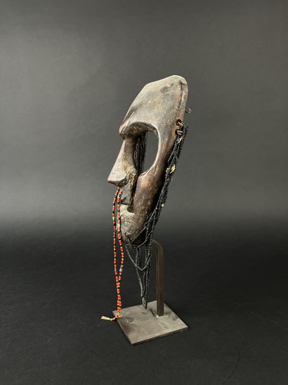Triangular shamanic mask with a human face,...