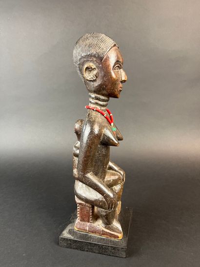 Mother seated on a stool with her child on...