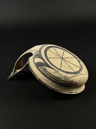 Kyathos, whose handle depicts a stylized...