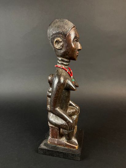 Mother seated on a stool with her child on...