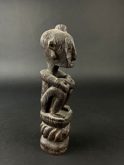 Seated figure with arms resting on knees....