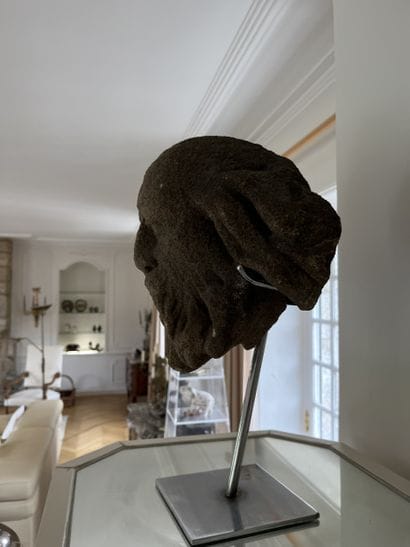 Carved granite head of a saint. Oval-shaped,...