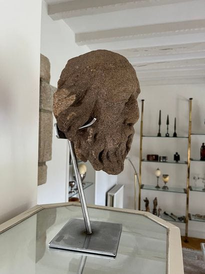 Carved granite head of a saint. Oval-shaped,...