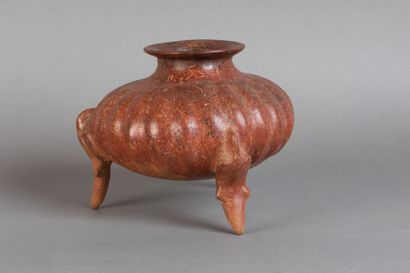 A tripod vase shaped like a pumpkin, resting...