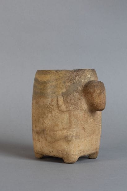 A rounded vase resting on four feet, carved...