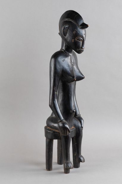 A female figurine depicted sitting on a stool....
