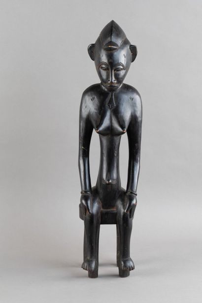 A female figurine depicted sitting on a stool....