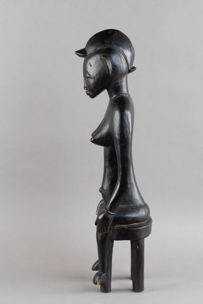 A female figurine depicted sitting on a stool....
