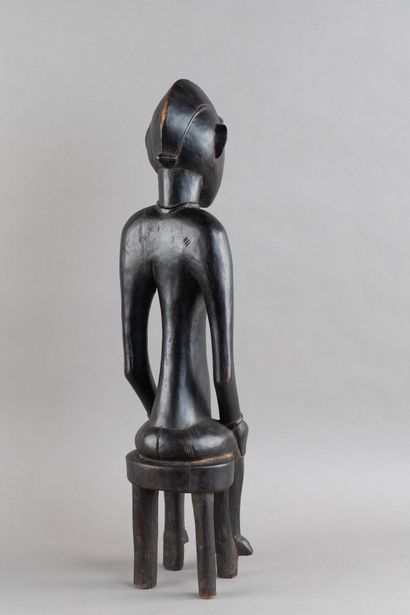 A female figurine depicted sitting on a stool....