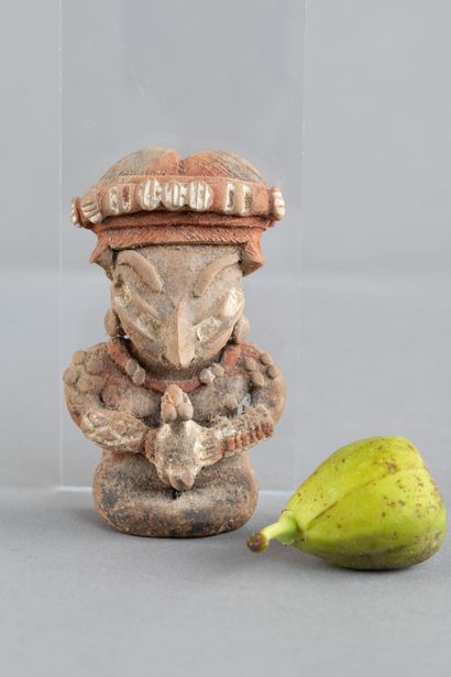 Female figurine depicted seated, holding...