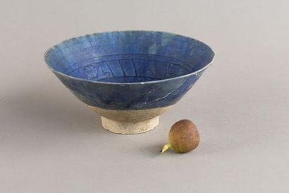 A cobalt-blue ceramic cup decorated with...