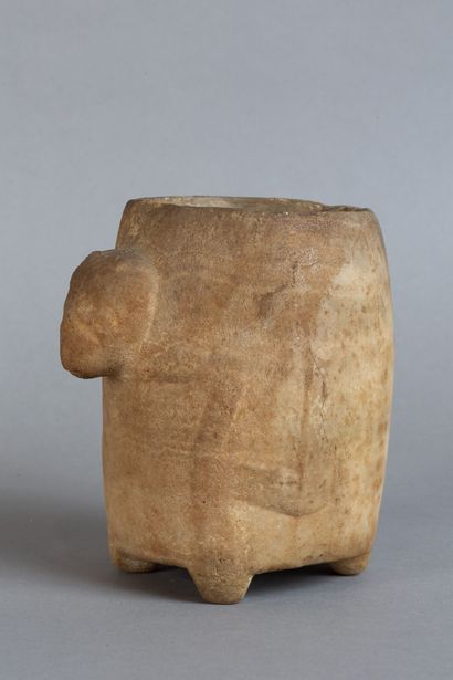 A rounded vase resting on four feet, carved...
