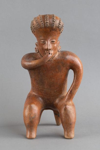 A statuette depicted sitting on a stool....