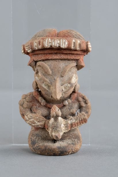 Female figurine depicted seated, holding...
