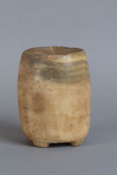 A rounded vase resting on four feet, carved...