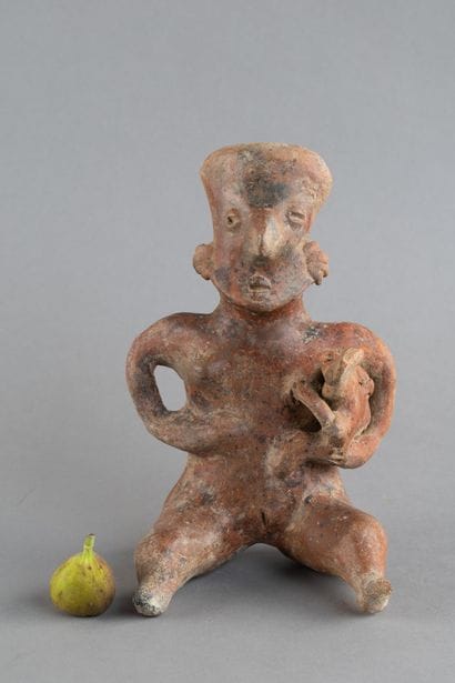A mother is depicted seated, holding her...