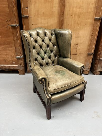 Fauteuil à oreilles en cuir capitonné vert...