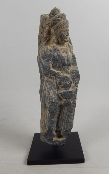 Femme debout, coiffée d'un chaperon de feuillage.En...