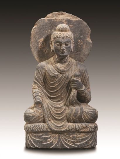 Bouddha auréolé assis sur un trône drapé....