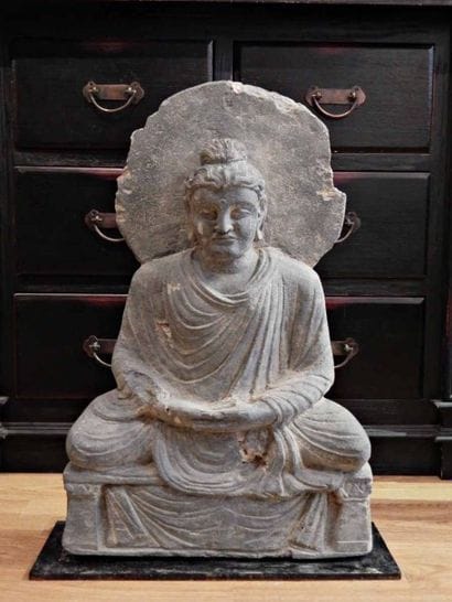 Bouddha auréolé, assis sur un trône drapé...