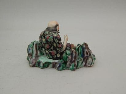 Vieillard assis en porcelaine émaillée polychrome....