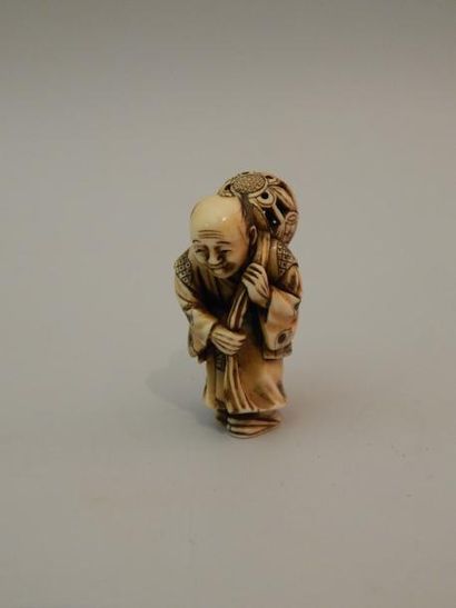 Netsuke en ivoire. Colporteur debout ayant...