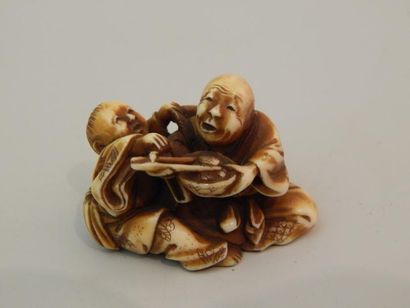 Netsuke en ivoire. Homme nourrissant son...