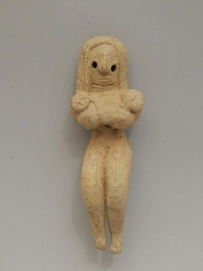Idole féminine assise, les mains placées...
