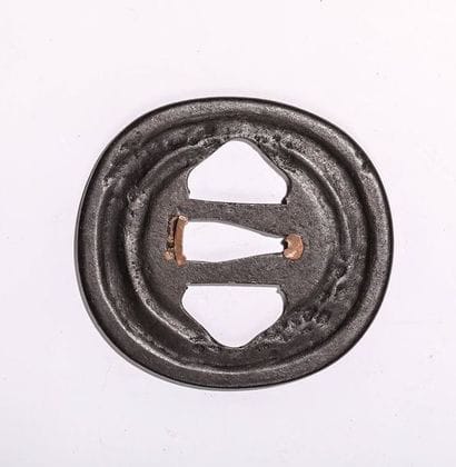 Tsuba en fer, à décor floral. H : 7,7 cm....