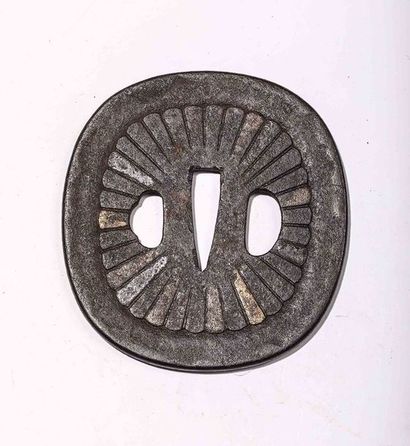 Tsuba en fer, à décor floral. H : 8,4 cm....