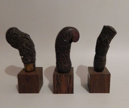Trois manches de kriss en bois, sur socle....