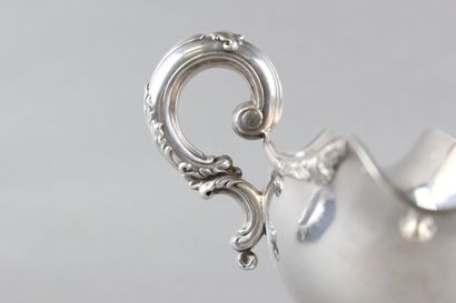 Sauceboat in silver on its polylobed display.

Decorated...
