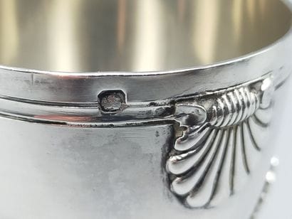 Coquetier tripode en argent à décor de coquilles....